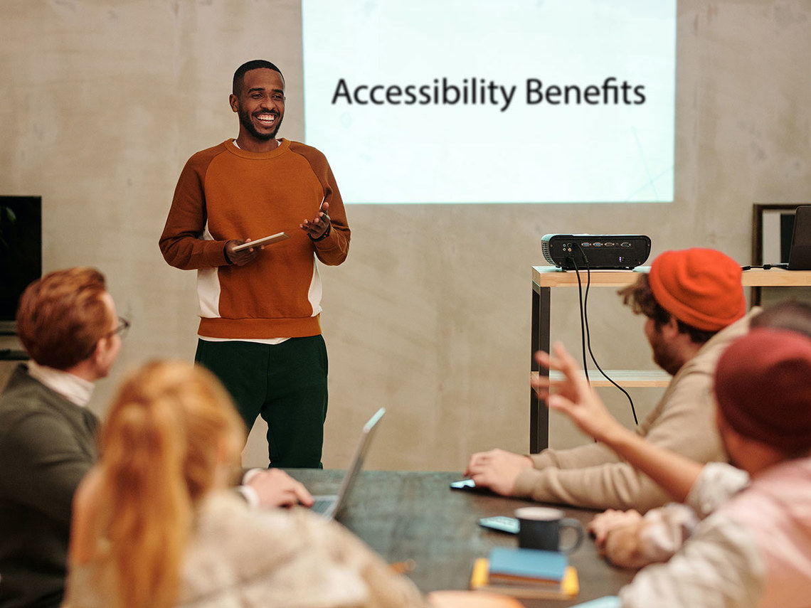 man standing presenting to coworkers about digital accessibility