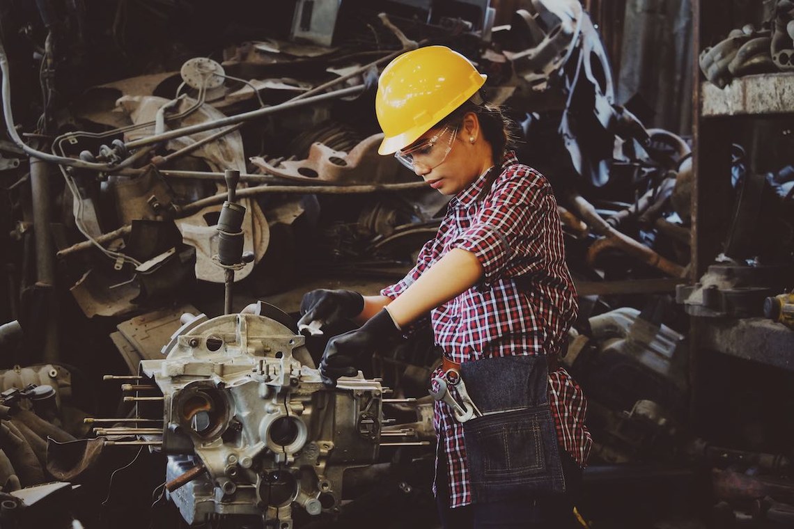 female mechanic in yellow hard hat working on engine - metaphor to shopify website remediation providers