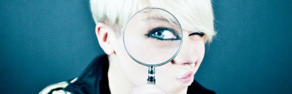 Woman with magnifying glass - metaphor for website google analytics & adwords auditing