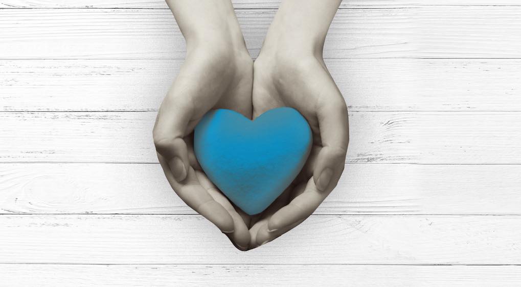 hands holding graphic of a blue heart